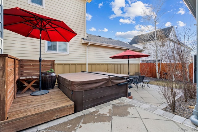 view of patio with a hot tub, fence, and a wooden deck