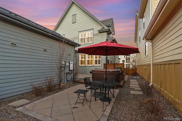 patio terrace at dusk with a hot tub and fence