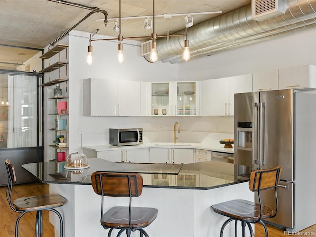 1499 Blake St Unit 3U, Denver, CO 80202 - kitchen featuring appliances with stainless steel finishes, a sink, a breakfast bar, and light wood-style floors