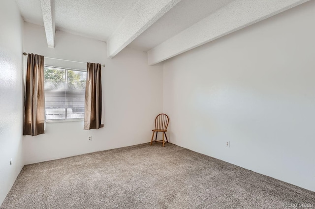 empty room featuring beam ceiling, carpet floors, and a textured ceiling