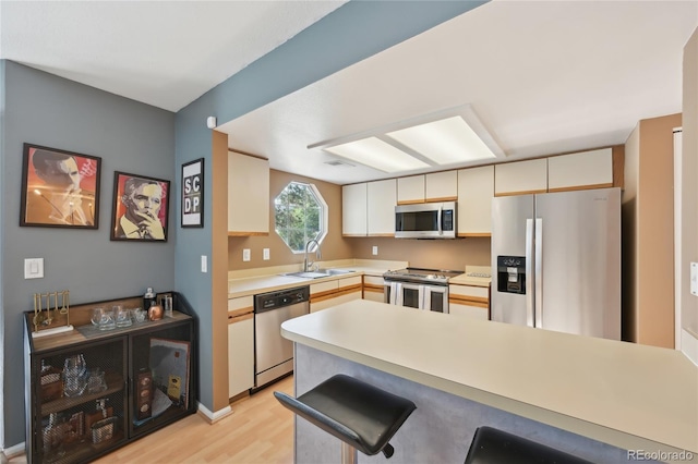 12655 E Pacific Cir Unit C, Aurora, CO 80014 - kitchen featuring stainless steel appliances, light wood-type flooring, light countertops, a breakfast bar area, and a peninsula