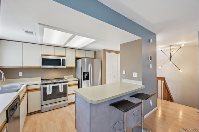 12655 E Pacific Cir Unit C, Aurora, CO 80014 - kitchen featuring stainless steel appliances, light countertops, light wood-style floors, a peninsula, and a breakfast bar area