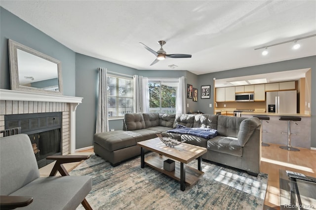 12655 E Pacific Cir Unit C, Aurora, CO 80014 - living area featuring wood finished floors, a ceiling fan, a brick fireplace, and bar area