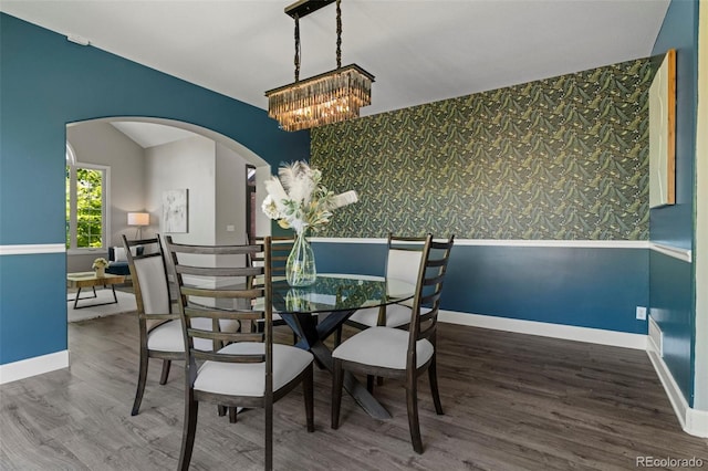 7119 S Riviera St, Aurora, CO 80016 - dining space with wallpapered walls, an accent wall, arched walkways, wood finished floors, and a chandelier