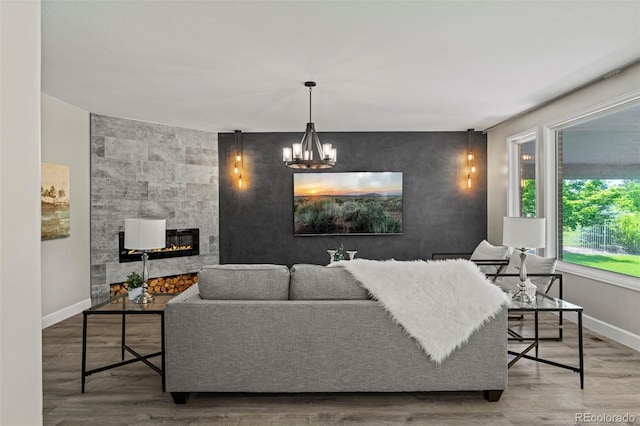 7119 S Riviera St, Aurora, CO 80016 - living area with a tiled fireplace, wood finished floors, an accent wall, and a chandelier
