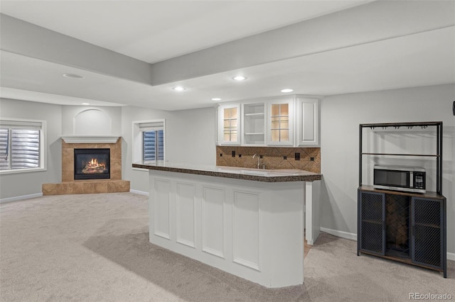 7119 S Riviera St, Aurora, CO 80016 - kitchen featuring stainless steel microwave, light carpet, dark countertops, white cabinets, and a fireplace