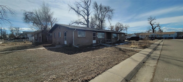 view of side of property featuring a residential view, fence, and brick siding