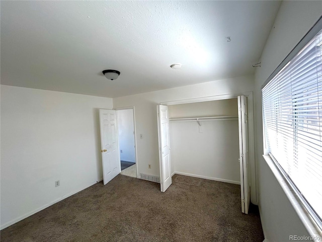 unfurnished bedroom with a closet, carpet, and baseboards