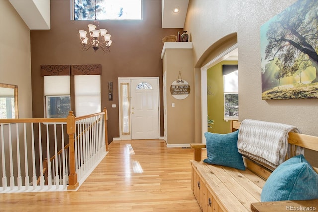 foyer entrance with a chandelier, a towering ceiling, and light hardwood / wood-style floors