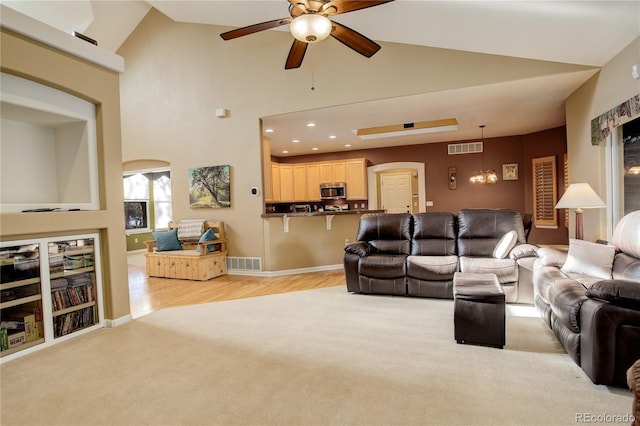 living room with ceiling fan with notable chandelier and high vaulted ceiling