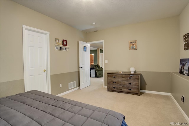 bedroom featuring light carpet and a textured ceiling