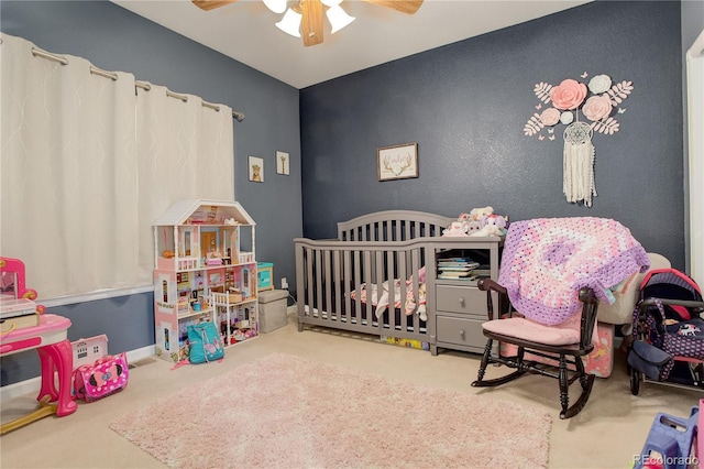 bedroom featuring ceiling fan, carpet floors, and a crib