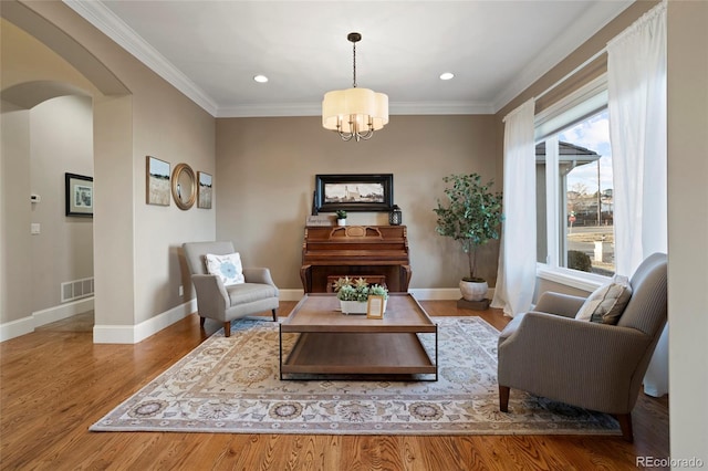 living area with ornamental molding, light hardwood / wood-style flooring, and a chandelier