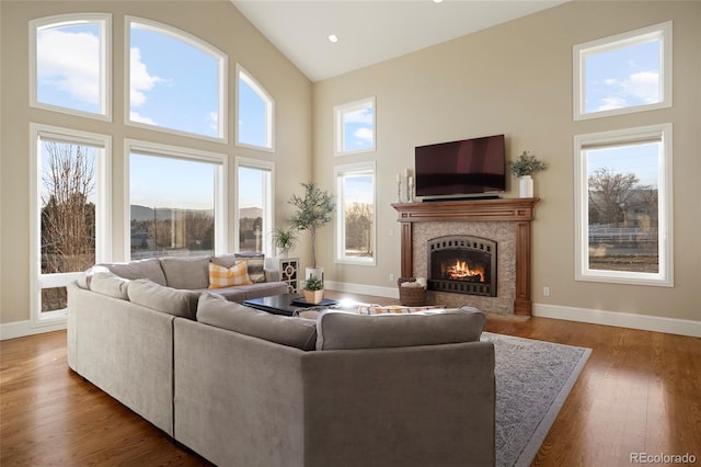 living room featuring a high end fireplace, hardwood / wood-style floors, and high vaulted ceiling