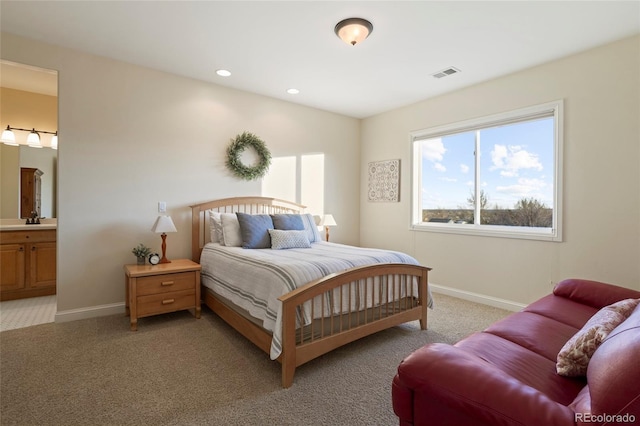 bedroom with sink, light carpet, and ensuite bath