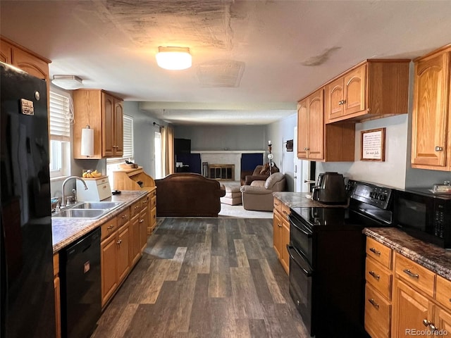 kitchen with black appliances, dark hardwood / wood-style flooring, sink, and a brick fireplace