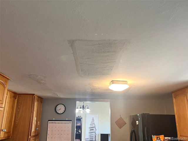 interior details with black fridge, a textured ceiling, and a notable chandelier