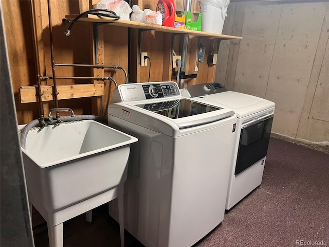 clothes washing area with dark colored carpet, washer and dryer, and sink