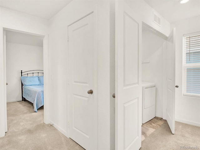 hallway with light colored carpet and independent washer and dryer