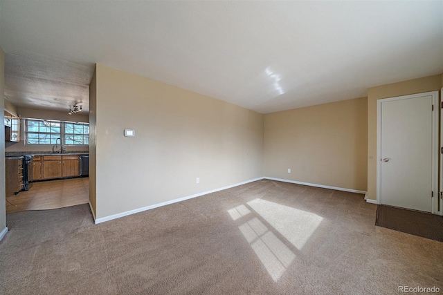 carpeted spare room with baseboards and a sink