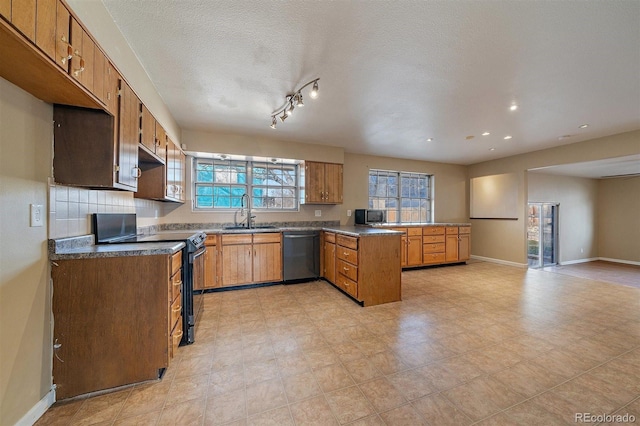 kitchen with baseboards, a peninsula, brown cabinetry, stainless steel appliances, and a sink