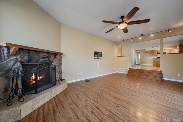 unfurnished living room with visible vents, ceiling fan, baseboards, light wood-type flooring, and a fireplace