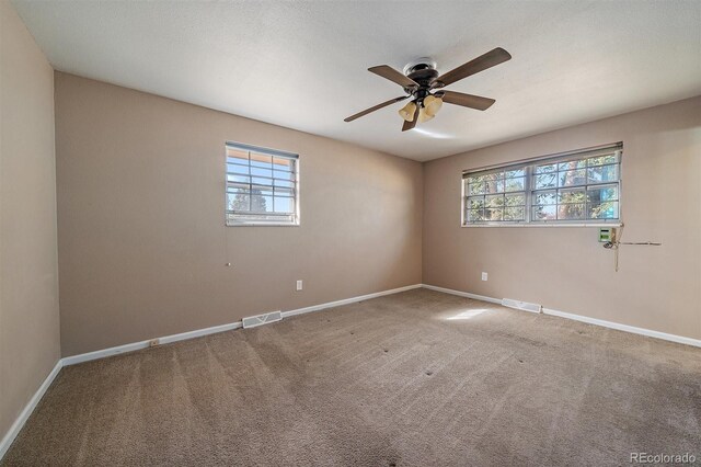 carpeted empty room featuring baseboards, visible vents, and ceiling fan