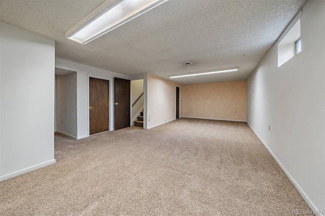 basement with a textured ceiling, baseboards, stairs, and carpet