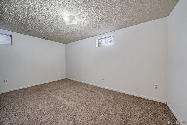 spare room featuring visible vents, baseboards, carpet, and a textured ceiling