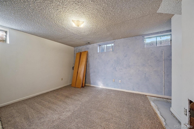 basement featuring carpet flooring, visible vents, a textured ceiling, and baseboards