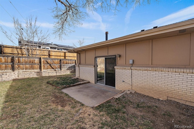 rear view of property featuring a patio area, brick siding, a lawn, and fence