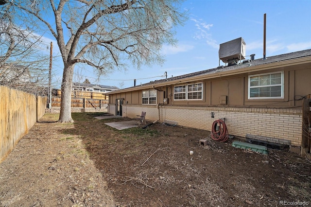 rear view of house featuring a fenced backyard, brick siding, and a chimney