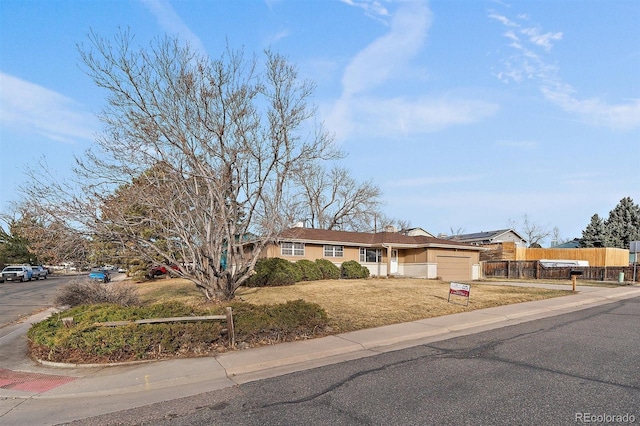 single story home with concrete driveway, an attached garage, fence, and a front yard