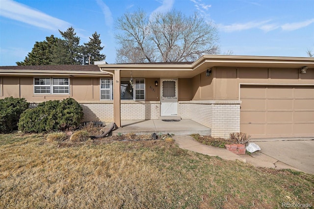 single story home with a porch, stucco siding, a front lawn, a garage, and brick siding