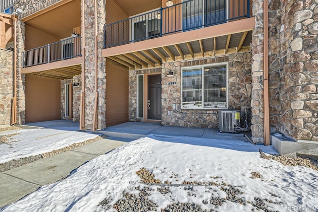 snow covered property entrance featuring central air condition unit