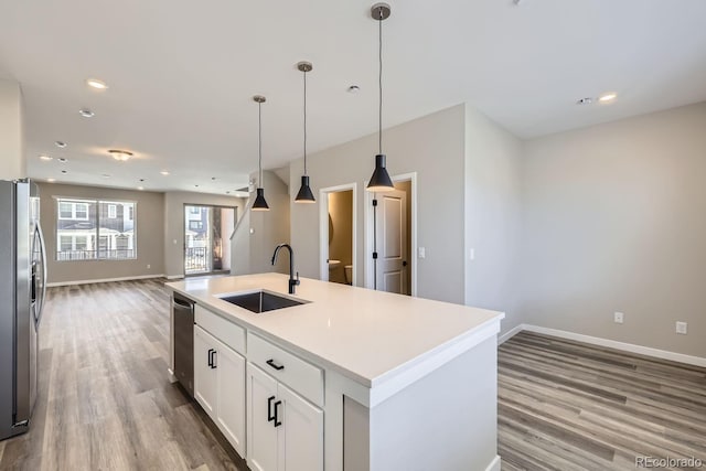 kitchen featuring sink, a kitchen island with sink, white cabinetry, stainless steel appliances, and decorative light fixtures