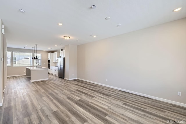 unfurnished living room with sink and light hardwood / wood-style floors