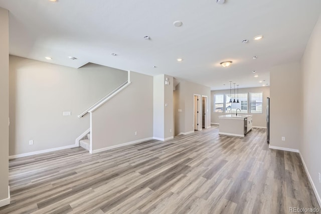 unfurnished living room featuring sink and light wood-type flooring