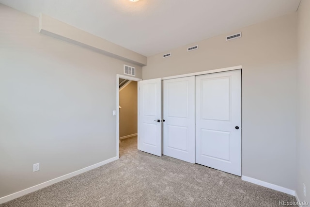 unfurnished bedroom with light colored carpet and a closet