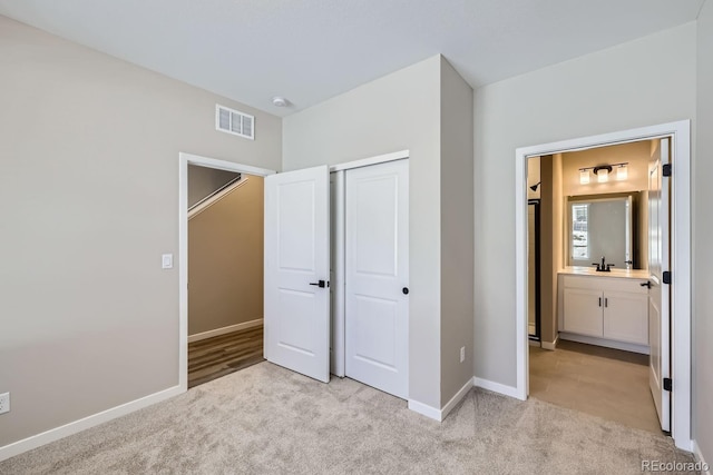 unfurnished bedroom with sink, light carpet, and a closet