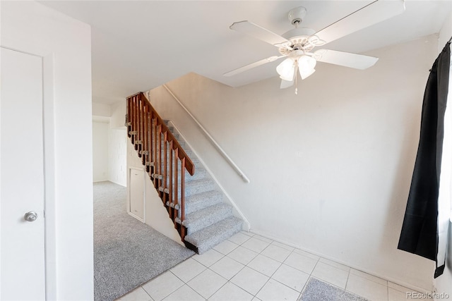 stairs with tile patterned floors, carpet flooring, and ceiling fan