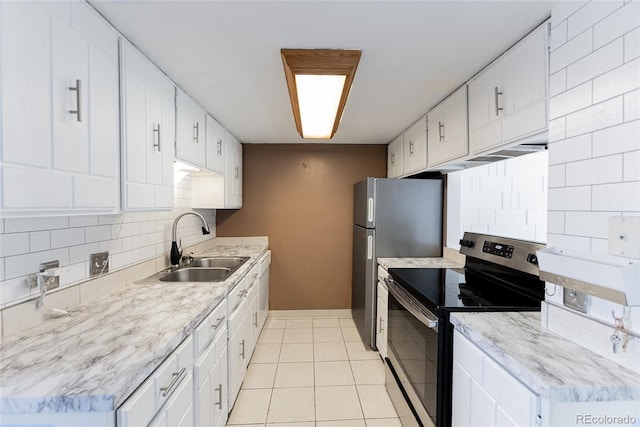 kitchen featuring tasteful backsplash, light countertops, light tile patterned floors, appliances with stainless steel finishes, and a sink