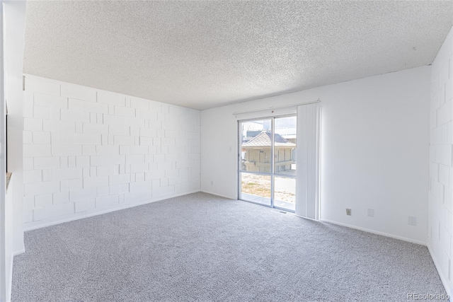 empty room featuring a textured ceiling, concrete block wall, and carpet floors