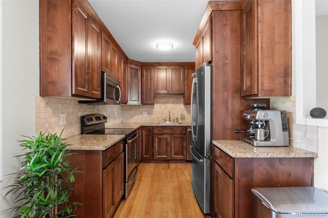 995 Ironton St, Aurora, CO 80010 - kitchen featuring stainless steel appliances, tasteful backsplash, light wood-type flooring, and light stone countertops