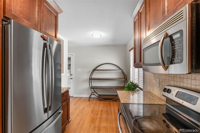 995 Ironton St, Aurora, CO 80010 - kitchen with stainless steel appliances, decorative backsplash, light wood finished floors, light stone countertops, and brown cabinetry