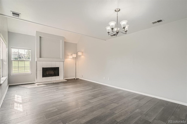 unfurnished living room featuring visible vents, an inviting chandelier, dark wood finished floors, and a tiled fireplace