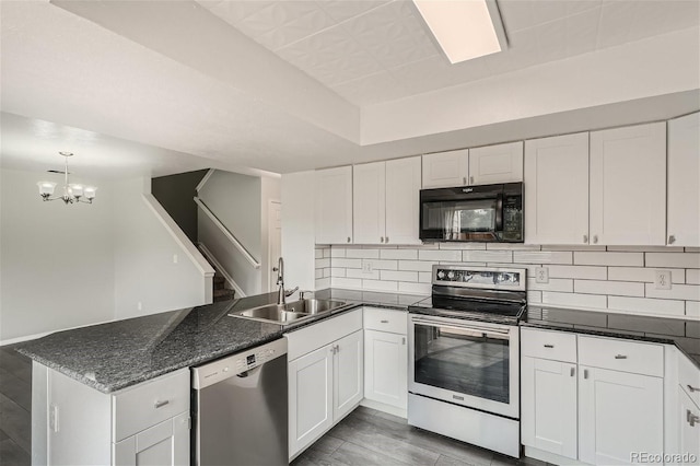 kitchen with a sink, backsplash, white cabinetry, stainless steel appliances, and a peninsula