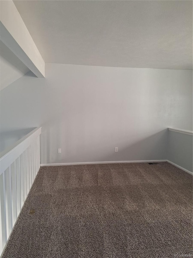 carpeted spare room with a textured ceiling and baseboards