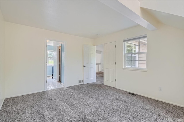 unfurnished bedroom with visible vents, multiple windows, and carpet