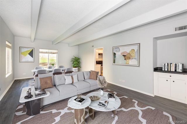 living room featuring dark hardwood / wood-style floors, beamed ceiling, and a textured ceiling